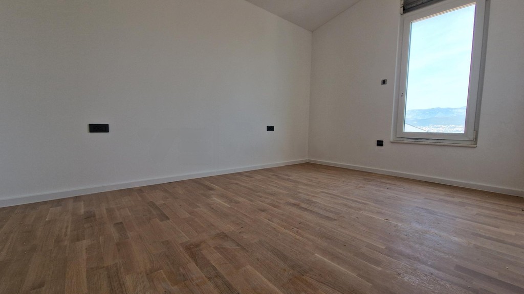 Empty room with parquet floor and a window overlooking mountains