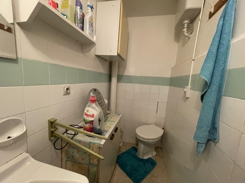 Small bathroom with light green tiles and shelf