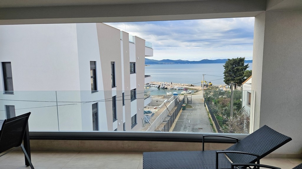 Dining area with table and chairs in a penthouse for sale in Zadar, Croatia, with window views of the sea
