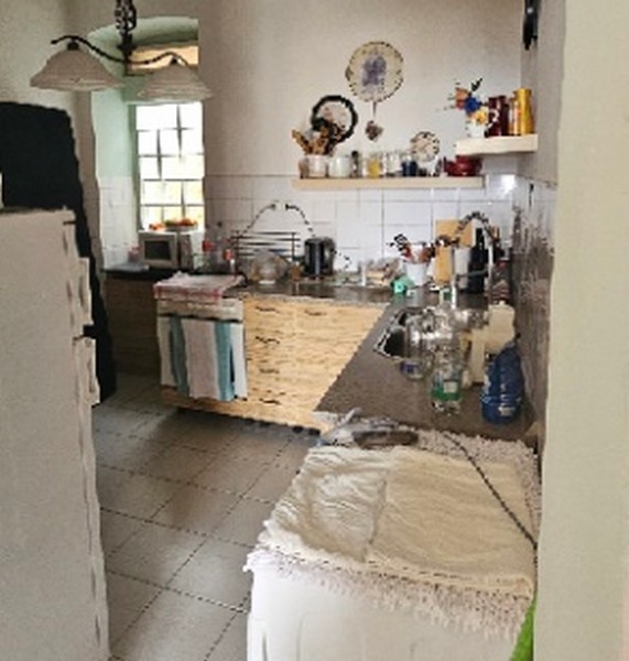 Kitchen interior with white tiles, various kitchen appliances and a long wooden counter