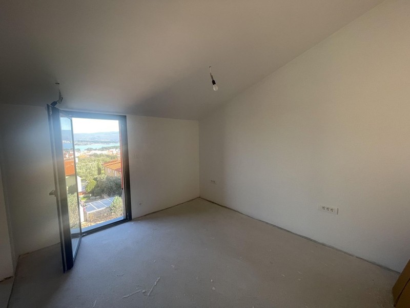 Empty room with sloped ceiling and floor-to-ceiling French door with sea view