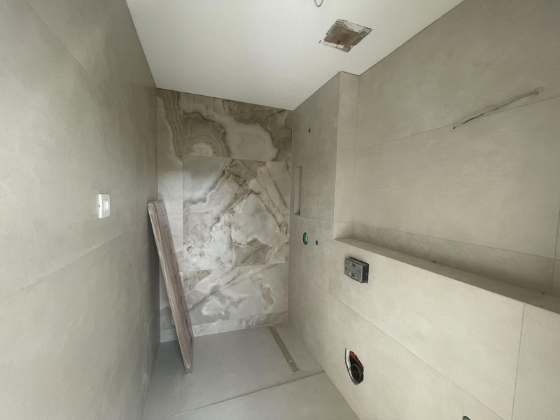 Bathroom under construction with tiled shower and marble-effect wall