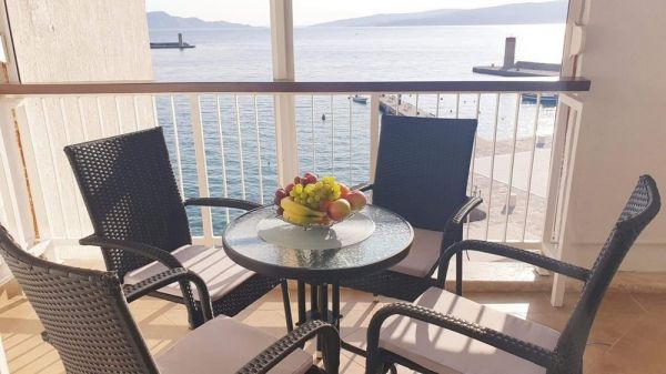 View of the sea from the balcony terrace of an apartment in Senj, with a table, chairs and a fruit basket