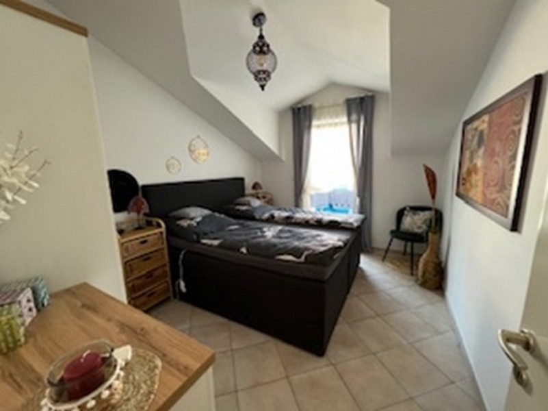Bedroom with sloping ceiling and dark box-spring bed