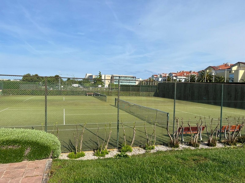 Tennis court with fence and benches in the complex