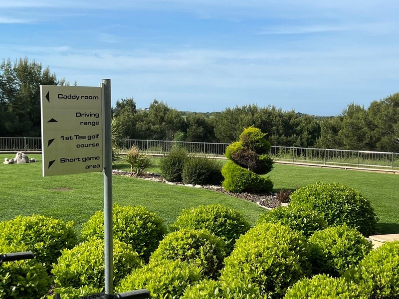 Well-kept garden area with signpost to driving range and golf course