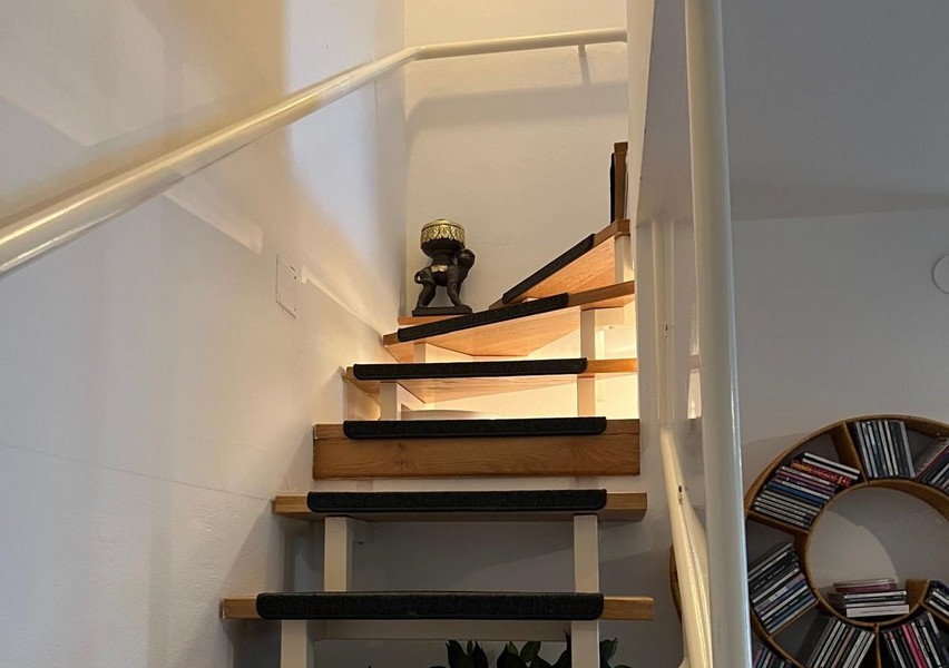 Open wooden staircase with handrail to the upper floor