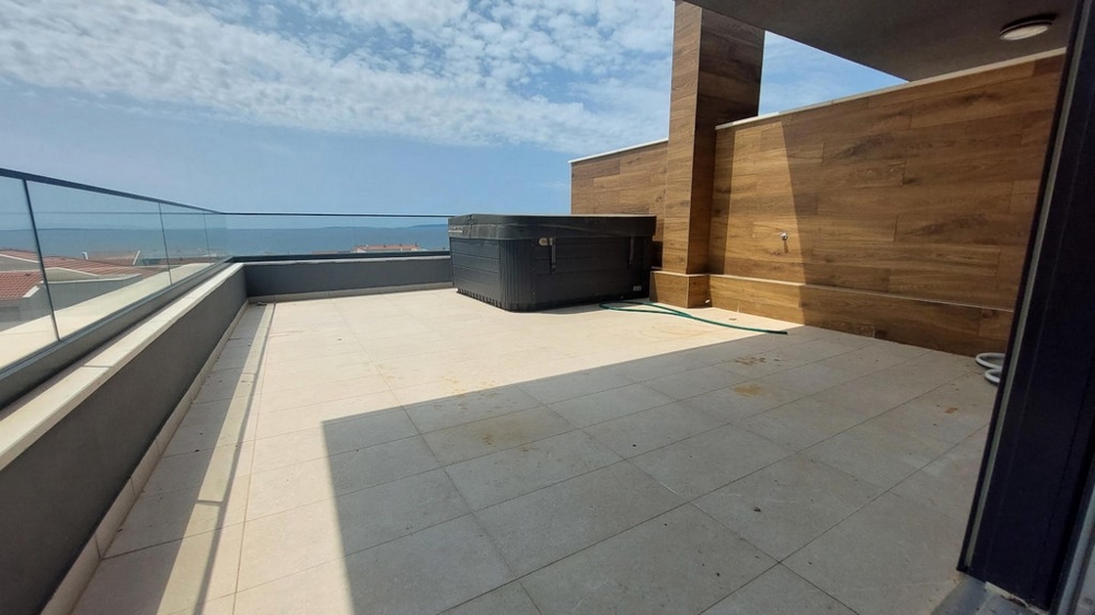 Spacious terrace with jacuzzi and sea views, light tiles and glass railings