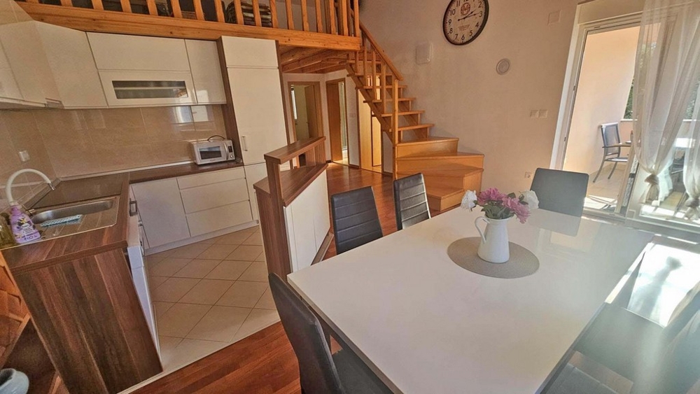 View of the dining area, the kitchen and the stairs to the gallery