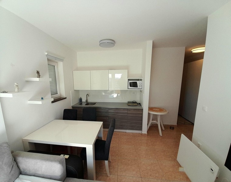 Bright living and kitchen area with tiled floors and access to the hallway