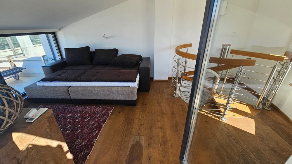 Gallery with sofa and spiral staircase to the lower level