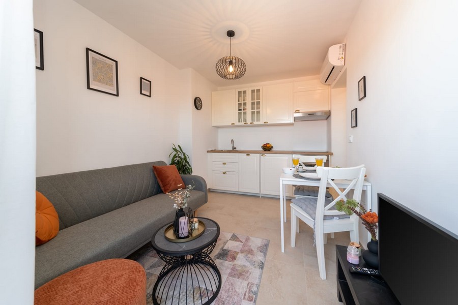 Living room with sofa, table and open kitchen