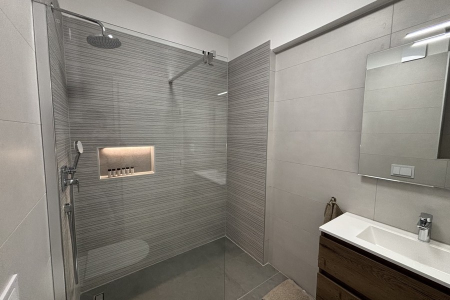 Bathroom with floor-level shower and vanity