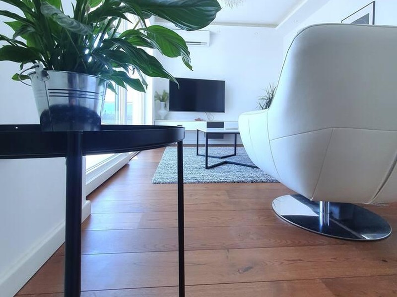Side table with plant and white armchair on parquet flooring