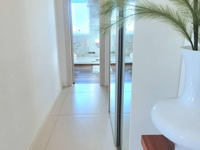 Bright hallway with mirrored wardrobe and view into the bathroom