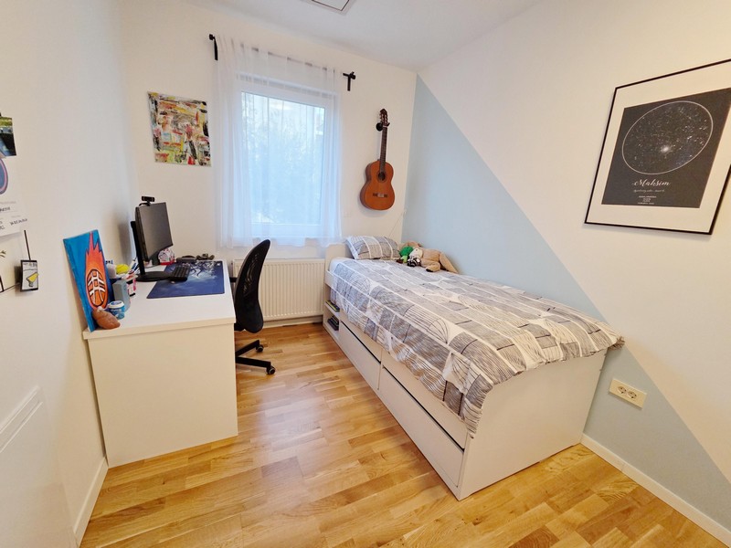 Teenager's bedroom with desk, bed and guitar on the wall