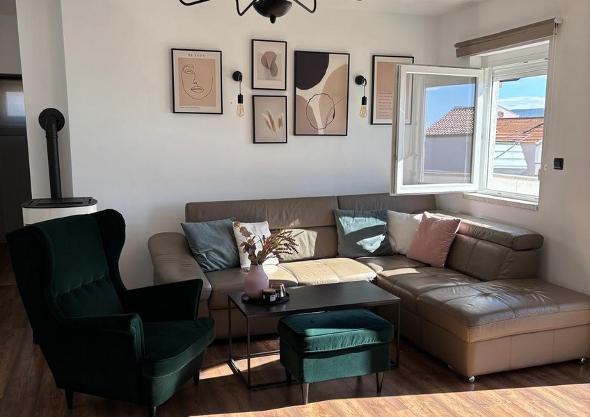 Living room with balcony access and views of the sea and coastal landscape