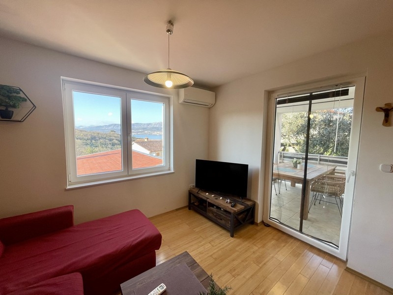 Living room with sofa, TV and balcony access overlooking the sea