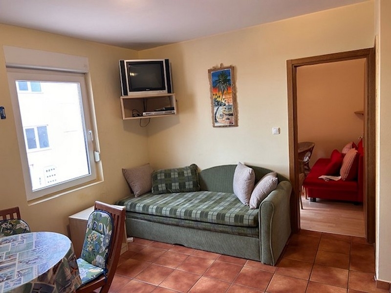 Compact living room with sofa, television and access to the bedroom