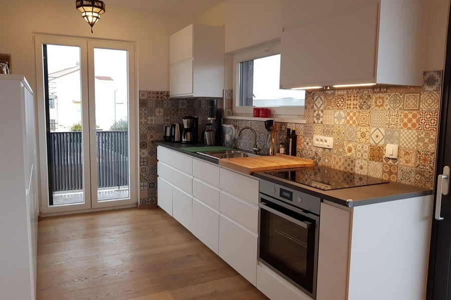 Modern kitchen with built-in appliances and decorative tiled splashback