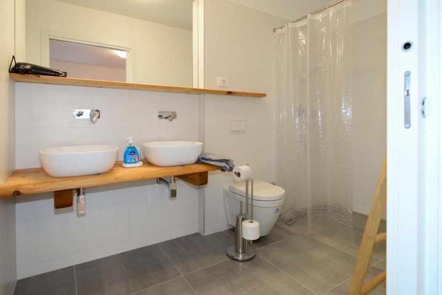 Modern bathroom with double sink, shower and toilet
