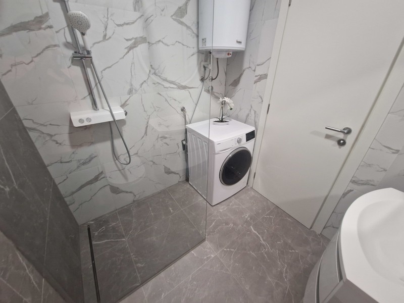Bathroom with floor-level shower and washing machine