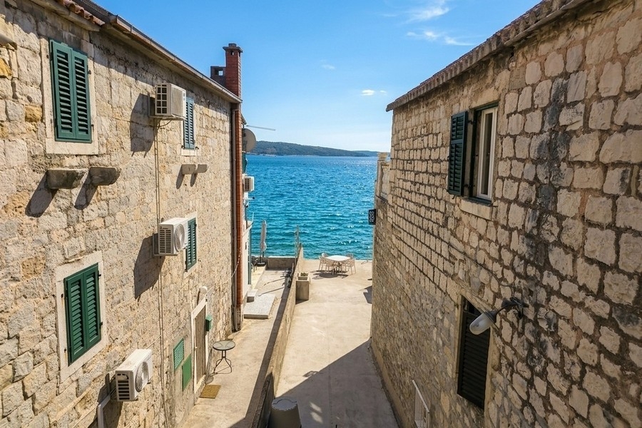 View of the sea between natural stone houses in Croatia