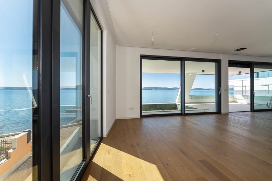 Living area with wooden floors and floor-to-ceiling windows with sea views