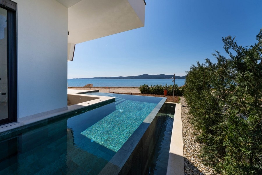 Pool of the apartment with plants and sea in the background