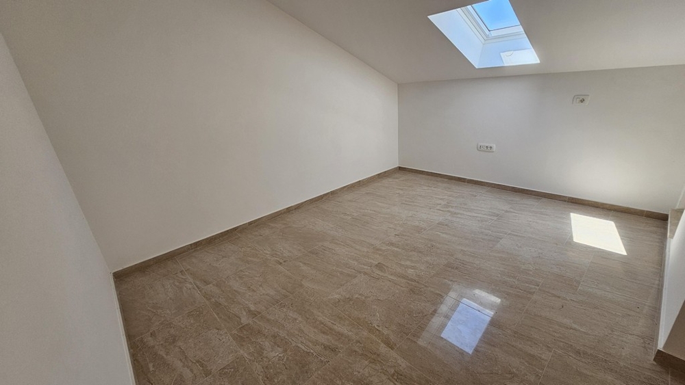 Room with skylight and light flooring