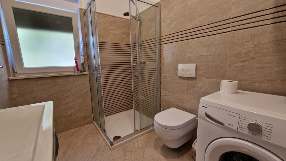 Bathroom with shower cabin and washing machine in Njivice
