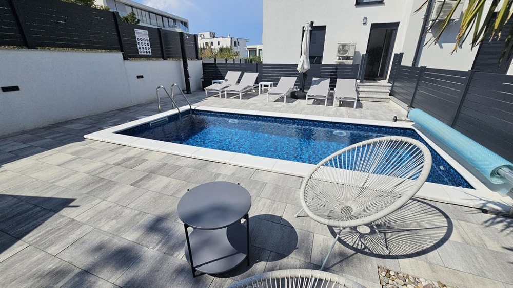 Heated pool with sun loungers in the garden of the apartment in Malinska on Krk