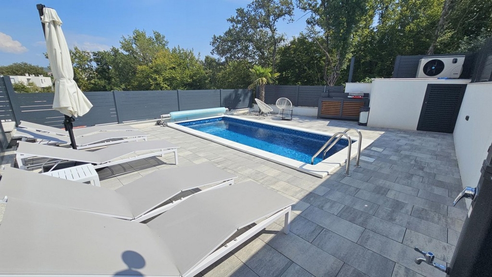 Garden with heated pool and sun loungers of the apartment in Malinska