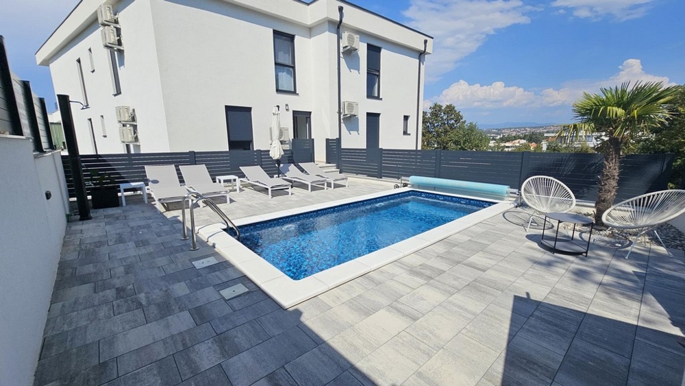 New building with pool and sun loungers in the garden in Malinska on the island of Krk