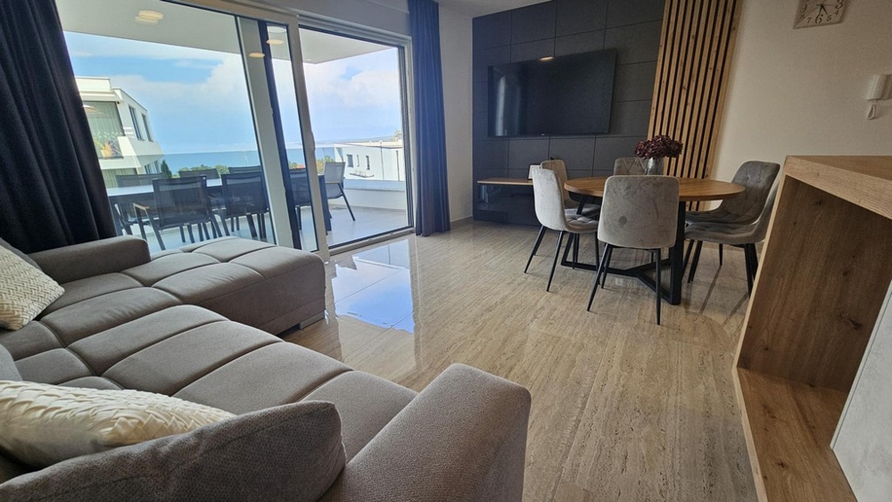 Living area with large window front and view of the terrace and the sea
