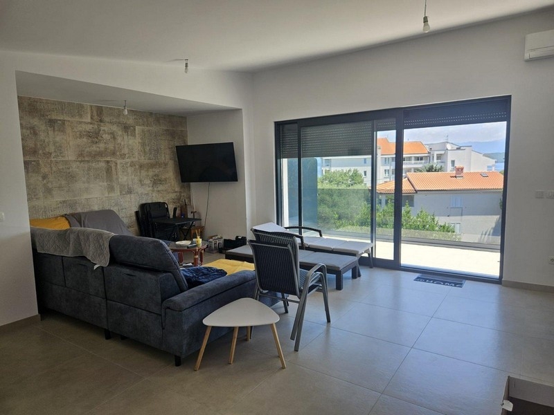 Living area with sofa, natural stone wall and access to the balcony