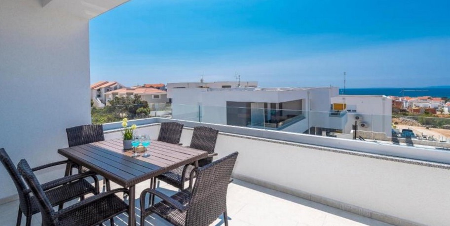 Covered terrace with dining table and view over Novalja