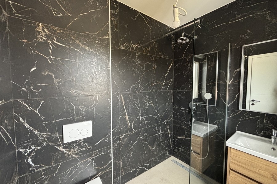 Bathroom with dark marble tiles and shower