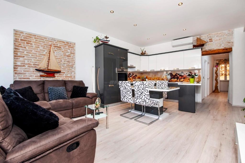 Living room with brick wall and open kitchen