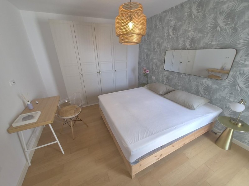 Double bed in front of patterned wallpaper