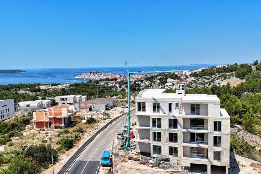 New-build building on the street, with sea and old town in the background