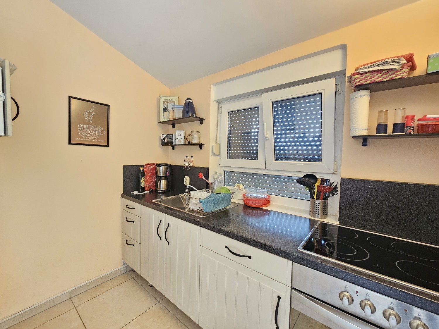 Kitchen with white fronts, ceramic hob and window