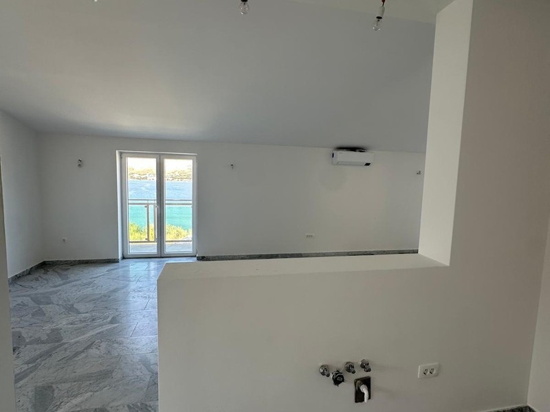 Living room with open kitchen area and window facing the sea