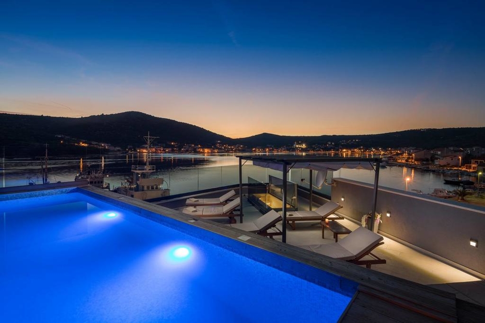 Illuminated pool with loungers above the harbour in the evening