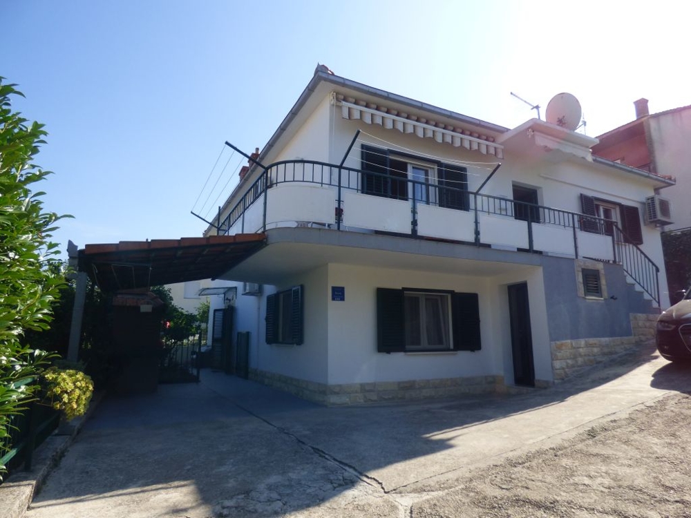 House with a wraparound balcony and a carport at the driveway