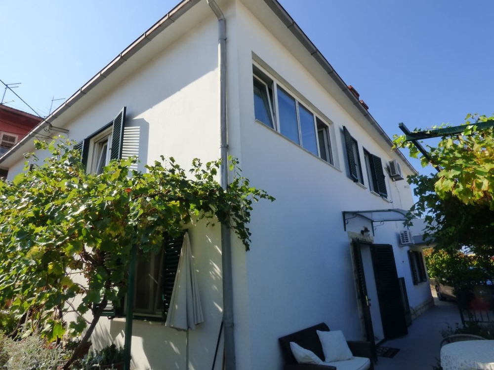 Corner of the house with vine leaves and a bench at the entrance