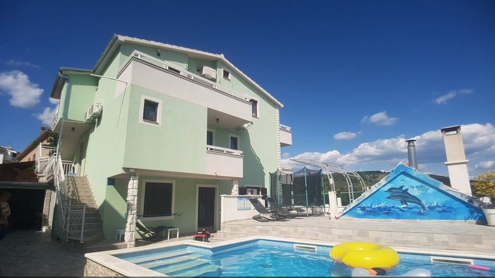 Green house with pool and pool cover in the yard