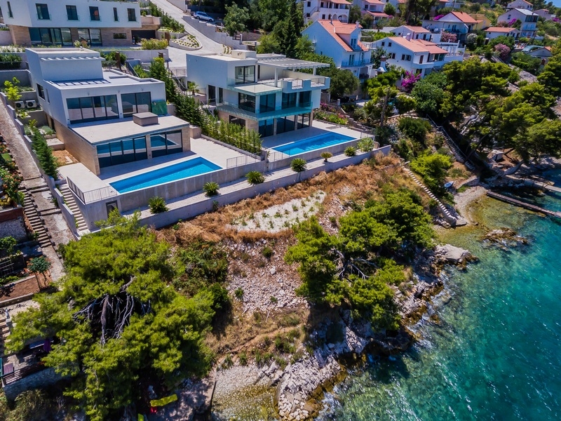 Aerial photo of two villas with pools directly above the water