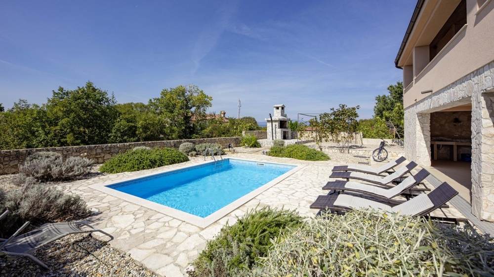 Pool with loungers and brick barbecue next to the house