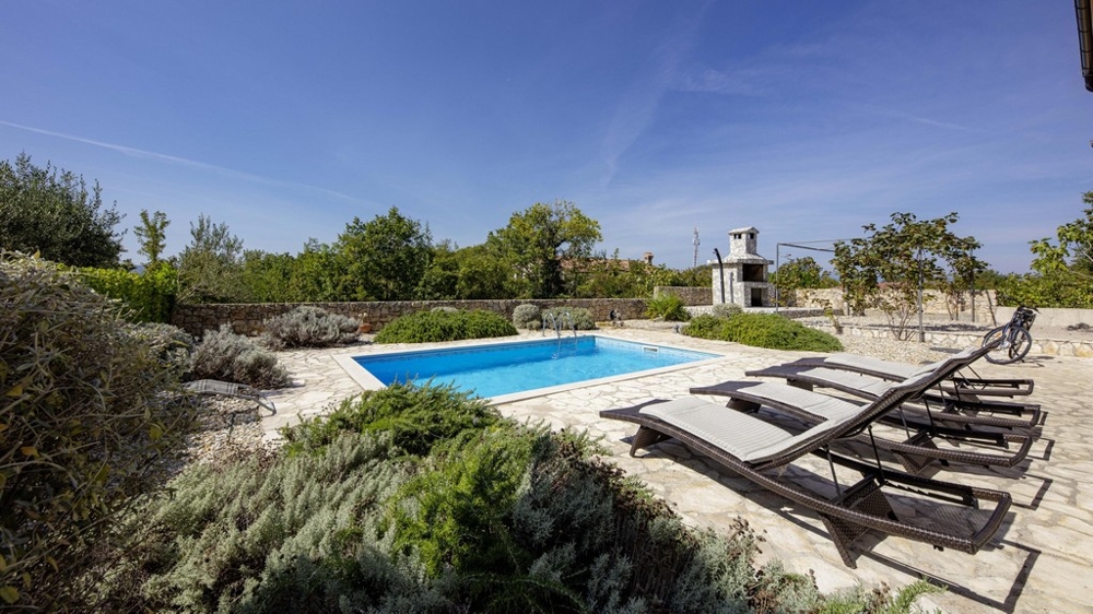 Pool with loungers between lavender and natural stone wall